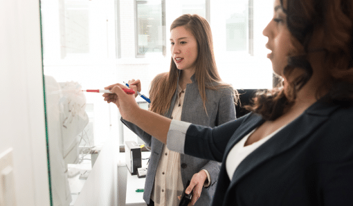 Two women working at a whiteboard