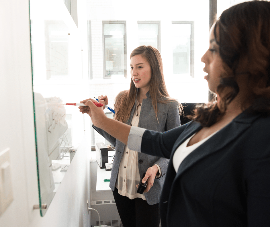 Two women working at a whiteboard